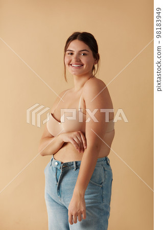 Overweight Woman. Happy Plus Size Woman Posing In Beige Lingerie And Jeans Overweight Woman. Happy Plus Size Woman Posing In Beige Lingerie And Jeans 98183949