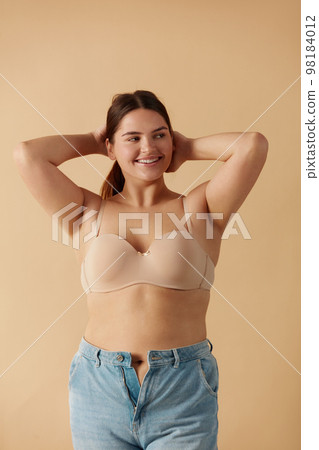 Overweight Woman. Happy Plus Size Woman Posing In Beige Lingerie And Jeans 98184012