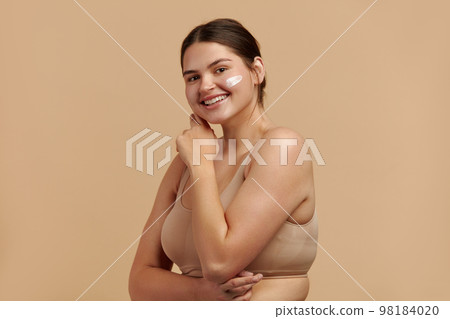 Positive Woman Applying Face Cream. Female Model Applying Cosmetic Product 98184020