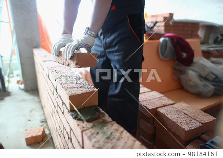 Construction mason builds brick wall in apartment 98184161