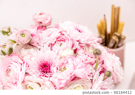 Feminine desktop with gold and pink stationery including fresh flowers 98184412