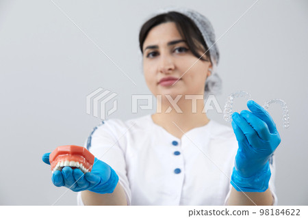 Dentist showing model of human jaw with wire braces and aligners to compare Dentist showing model of human jaw with wire braces and aligners to compare 98184622