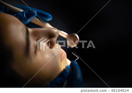 Dentist checking teeth of a female patient with dental mirror 98184624