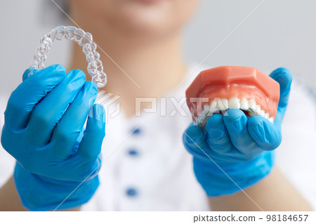 Orthodontist showing the system of aligners on artificial jaws 98184657