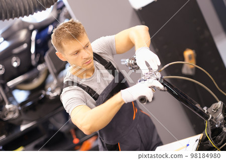 Auto mechanic repairs motorcycle fork in workshop 98184980