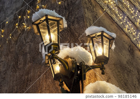 Vintage Christmas lanterns burning with a candle hanging on a house on a blurred background. Vintage Christmas lanterns burning with a candle hanging on a house on a blurred background. 98185146