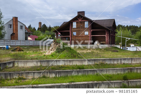 Brown wooden house under a gray roof against a blue sky. building architecture. 98185165