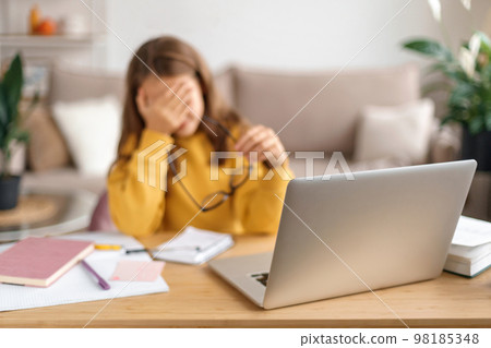 Portrait of sad kid girl tired from studying, learning online from home with laptop Portrait of sad kid girl tired from studying, learning online from home with laptop 98185348
