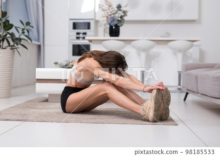 Inflexible woman improving flexibility by working out at home 98185533