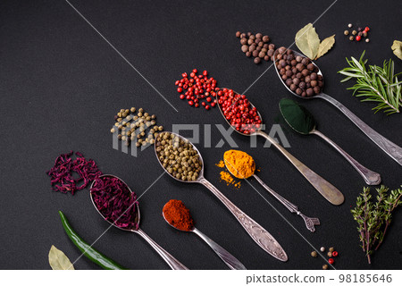 Several types of spices in metal spoons paprika, tomatoes, curry, beets, cumin, turmeric, fennel, spirulina 98185646