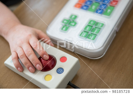 Woman with cerebral palsy works on a specialized computer mouse. 98185728