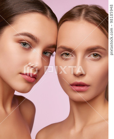 Perfection. Portrait of two young, beautiful girls with well-kept fresh skin isolated over pink studio background. Concept of skincare, cosmetology, natural beauty Perfection. Portrait of two young, beautiful girls with well-kept fresh skin isolated over pink studio background. Concept of skincare, cosmetology, natural beauty 98185948