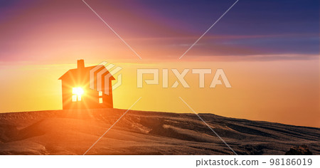 Model of house on sunset evening. Silhouette house standing on ground on sunrise background. Real estate agent offer new house to buy and for rent. banner. copy space. 98186019