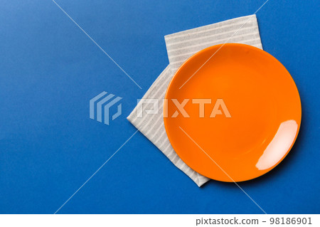 Top view on colored background empty round red plate on tablecloth for food. Empty dish on napkin with space for your design Top view on colored background empty round red plate on tablecloth for food. Empty dish on napkin with space for your design 98186901
