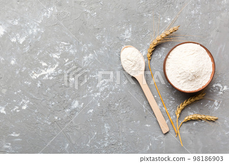 Flat lay of Wheat flour in wooden bowl with wheat spikelets on colored background. world wheat crisis 98186903