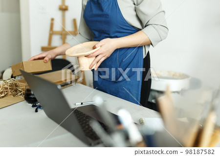 Unrecognisable woman entrepreneur, Business owner working at home office with her clay ceramic product. Online selling business work Unrecognisable woman entrepreneur, Business owner working at home office with her clay ceramic product. Online selling business work 98187582
