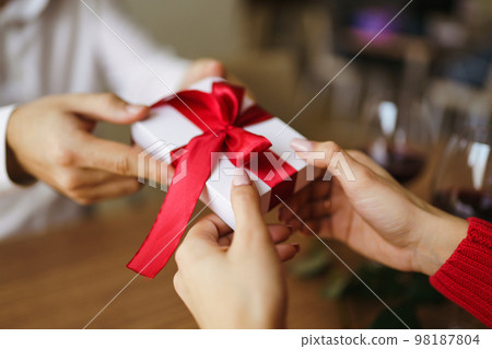 Man gives to his woman a gift box with red ribbon. Hands of man gives surprise gift box for girl. 98187804