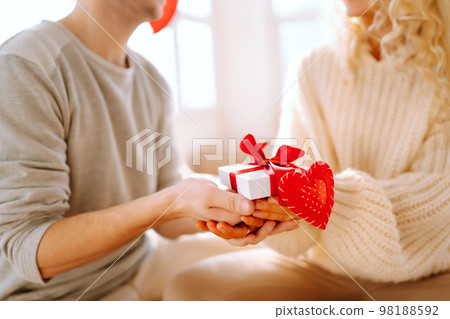 Beautiful young couple at home celebrating Valentine's Day. Lovers give each other gifts. Beautiful young couple at home celebrating Valentine's Day. Lovers give each other gifts. 98188592