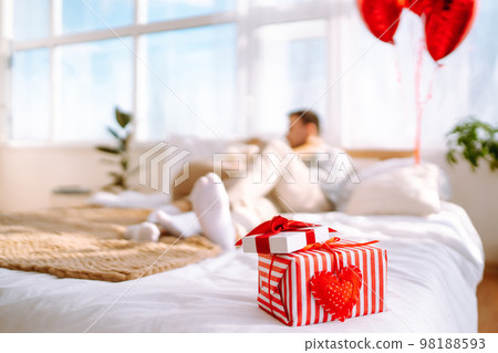 Beautiful young couple at home celebrating Valentine's Day. Lovers give each other gifts. Beautiful young couple at home celebrating Valentine's Day. Lovers give each other gifts. 98188593