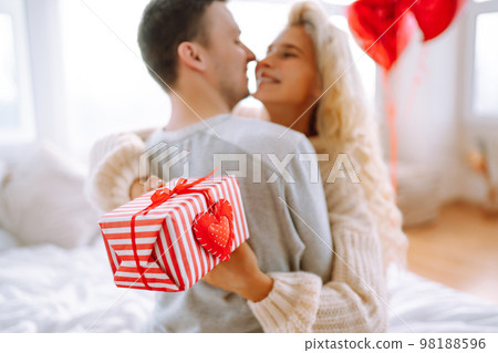 Beautiful young couple at home celebrating Valentine's Day. Lovers give each other gifts. 98188596