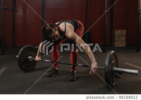 Young crossfit woman preparing barbell for lifting weight at the gym. 98189022