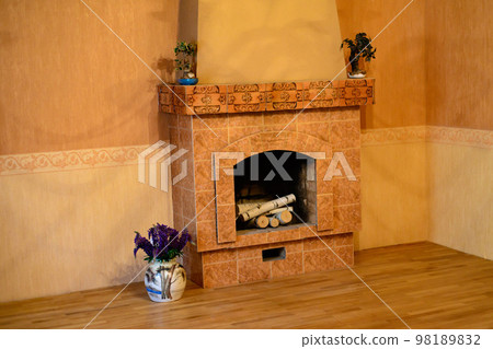 fireplace with wood in a rustic cottage, near a vase with flowers 98189832