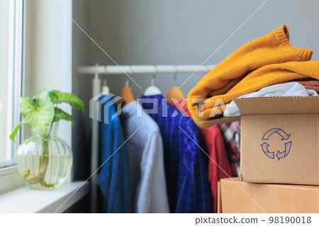 recycling, old clothes in cardboard box. textiles, paper at home and hand over 98190018
