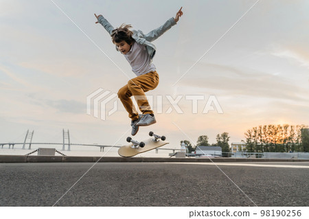 Boy jumping on skateboard at the street. Boy jumping on skateboard at the street. 98190256