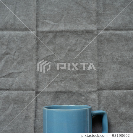 Blue mug cup on gray fabric background. top view Blue mug cup on gray fabric background. top view 98190602