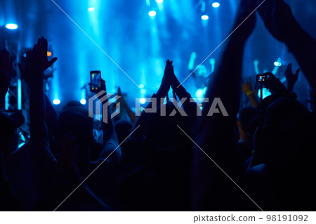 People taking photographs with smart phone during a music festival. Fans enjoying rock concert with light. 98191092