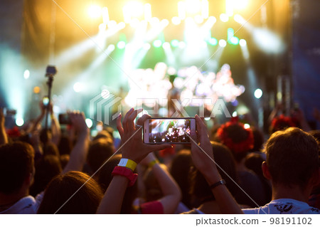 Hand with a phone records live music festival. People taking photographs with smart phone during concert. Hand with a phone records live music festival. People taking photographs with smart phone during concert. 98191102