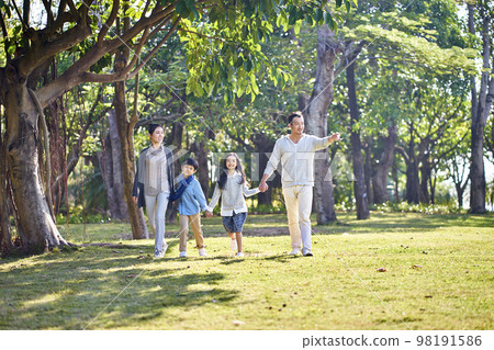 asian family with two children walking hand in hand outdoors in park asian family with two children walking hand in hand outdoors in park 98191586
