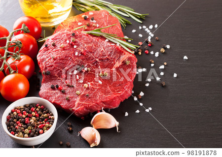 Raw steak with cooking ingridients on black slate background Raw steak with cooking ingridients on black slate background 98191878