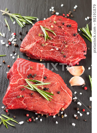 Raw steak with cooking ingridients on black slate background Raw steak with cooking ingridients on black slate background 98191879