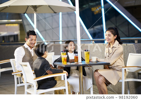 happy asian family with two children relaxing talking having drinks and desserts at an outdoor coffee place 98192060