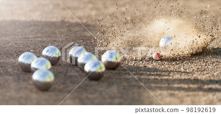 Petanque ball boules bowls on a dust floor, photo in impact. Game of petanque on the ground. Balls and a small wood jack Petanque ball boules bowls on a dust floor, photo in impact. Game of petanque on the ground. Balls and a small wood jack 98192619