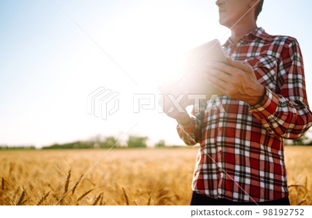 Smart farm. Farmer with a tablet in his hands on an agricultural field. Harvesting. Smart farm. Farmer with a tablet in his hands on an agricultural field. Harvesting. 98192752