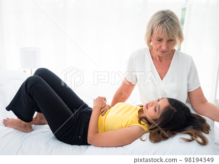 The adopted caucasian mother care of her Asian teen daughter while she is sleeping on his lap. love and sharing time of stepmother, stepdaughter concept. 98194349