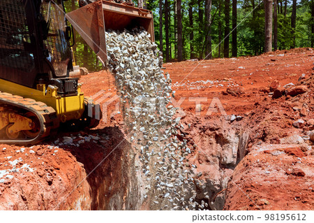 Excavator machine working on construction areas unloading a stone gravel 98195612