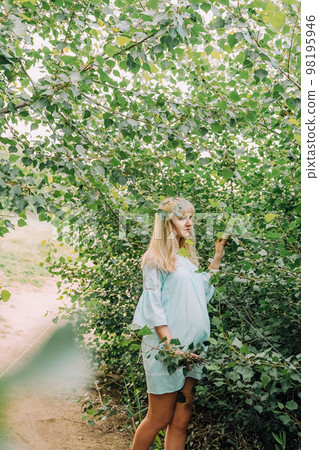 Happy pregnant woman in blue dress in garden Happy pregnant woman in blue dress in garden 98195946