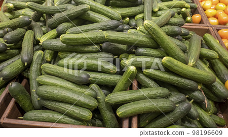Cucumber background. Close-up of fresh long cucumbers on the store counter 98196609