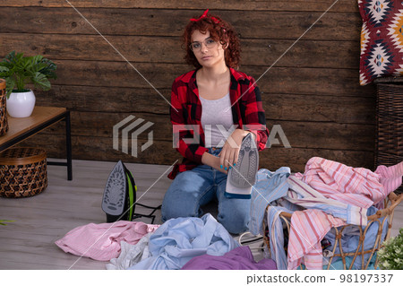 A young woman in a not-so-good mood before starting to iron clothes. A young woman in a not-so-good mood before starting to iron clothes. 98197337