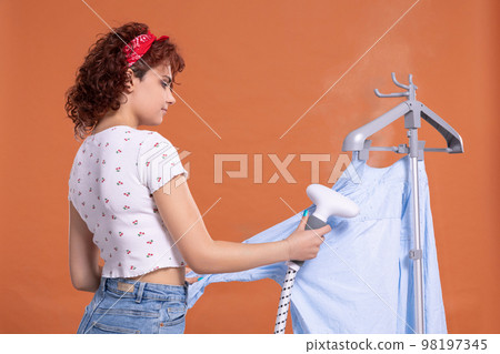 Steamer for ironing shirts and other clothing. Girl with curly hair. 98197345