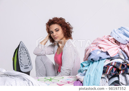 The woman can't believe she has so many men's shirts to iron this time. 98197352