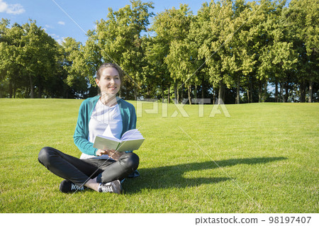 Young pretty woman on the lawn with a book in their hands. Education and knowledge Young pretty woman on the lawn with a book in their hands. Education and knowledge 98197407