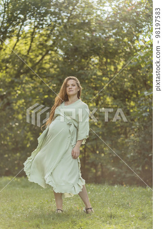 Dancing pretty regnant woman with big belly, green trees, meadow on background. White female wears dress. Magic happy pregnancy. Baby shower, childbirth, emotional connection with baby. Vertical Dancing pretty regnant woman with big belly, green trees, meadow on background. White female wears dress. Magic happy pregnancy. Baby shower, childbirth, emotional connection with baby. Vertical 98197583