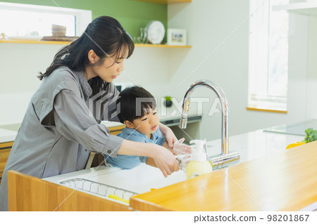 Child and mother washing hands in the kitchen Child and mother washing hands in the kitchen 98201867