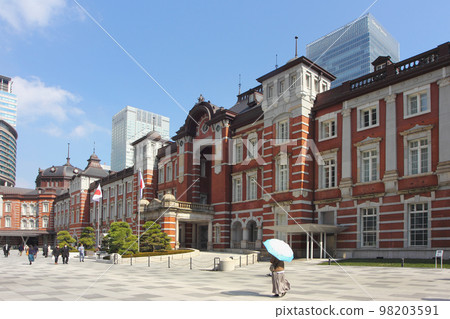 紅磚東京站和高樓寫字樓在蔚藍的天空中生長，打著遮陽傘的婦女們輕盈地走著。 98203591