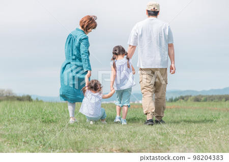 Back view of family/family walking in park/grassland in spring/summer (children/parents/migration/country life) 98204383