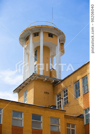 Creative old building with a tower against the background of the evening sky.Old factory Creative old building with a tower against the background of the evening sky.Old factory 98206040